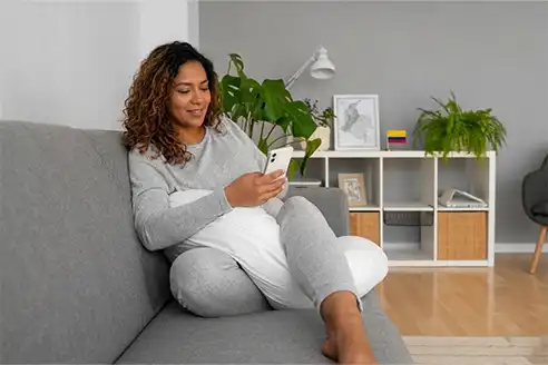 Mujer colombiana en casa agendando una visita técnica de ManteniCentro desde su celular para la reparación de un electrodoméstico o aire acondicionado